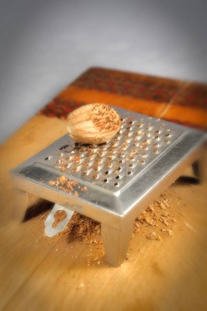 Foto de Cosas de cocina, nuez moscada en rallador sobre tabla de madera - Imagen libre de derechos