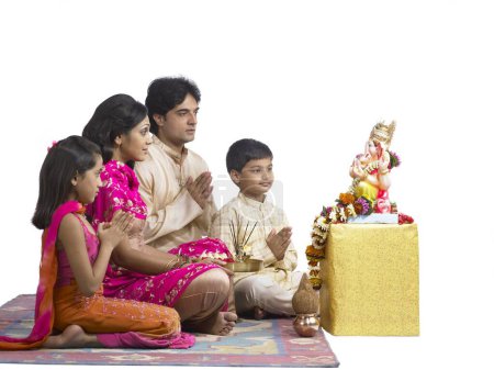 Téléchargez les photos : Famille indienne sud-asiatique avec père mère fils et fille assis priant le seigneur Ganesha - en image libre de droit