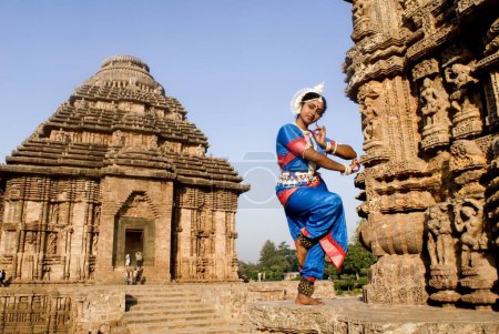 Téléchargez les photos : La pose de la danseuse Odissi reproduit des mythes indiens tels que le Ramayana devant le complexe du temple solaire du patrimoine mondial à Konarak, Orissa, Inde - en image libre de droit