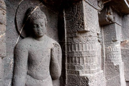 Téléchargez les photos : Bouddha debout avec fleur à la main l'une des statues de grand seigneur au site du patrimoine mondial de l'UNESCO Grottes Ajanta dans le Maharashtra, Inde - en image libre de droit