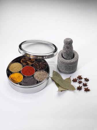 Different types of spices in bowls in stainless steel box with old stone grinder
