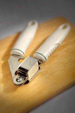 Photo for Kitchen things , garlic press on wooden board - Royalty Free Image