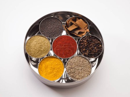 Different types of spices in bowls in stainless steel box on white background