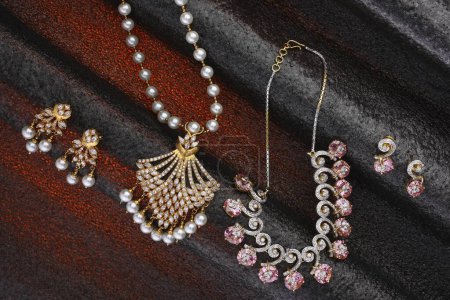 Foto de Collar de joyas de oro diamante y orejeras sobre fondo rojo negro - Imagen libre de derechos