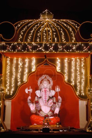 Téléchargez les photos : Idole du seigneur Ganesh dieu tête d'éléphant maintenu dans un cadre joliment décoré de lumières illuminées, festival Ganpati à Pune, Maharashtra, Inde - en image libre de droit