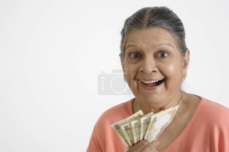 Alte Dame hält fünf Scheine zu je 500 Rupien in der Hand und lacht