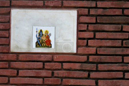 Photo for Red brick wall with tile designed with impression of god Shiva goddess Parvati and Lord Ganesha - Royalty Free Image