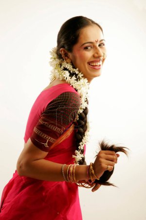 South Asian Indian Maharashtrian girl wearing traditional navwari nine yard sari with appropriate jewellery and flower garland in hair called gajra showing long platted hair 