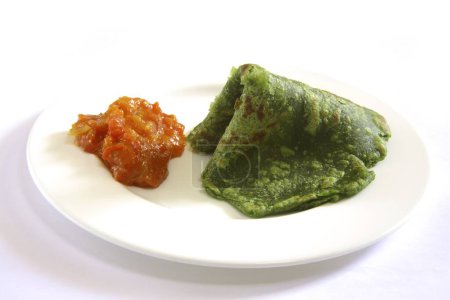 Foto de Cocina india, comida rápida crujiente Palak Spinach Puri con tomates masala bhaji o sabzi servidos en plato sobre fondo blanco - Imagen libre de derechos