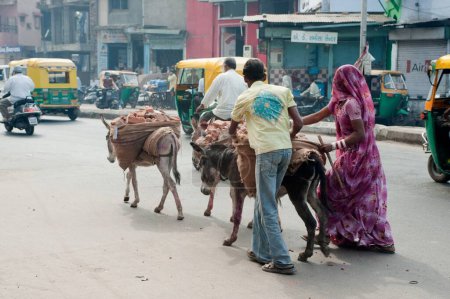 Photo for Man and woman carrying brick on donkeys back , Ahmedabad , Gujarat , India - Royalty Free Image