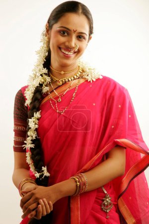 South Asian Indian Maharashtrian girl wearing traditional navwari nine yard sari with appropriate jewellery with flower garland in hair called gajra smiling innocently 