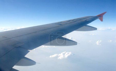 Téléchargez les photos : Transport aérien, vue de l'aile et des nuages dans le ciel bleu depuis la fenêtre de l'avion - en image libre de droit