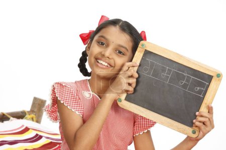 Ten years old girl showing four Marathi devnagri alphabets written on slate 