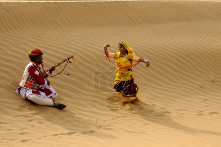 Foto de Pareja tocando música folclórica y bailando en dunas de arena, Jaisalmer, Rajasthan, India - Imagen libre de derechos