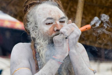 Hindú santa naga baba Shivdasgiri fumar tabaco en Varanasi en el río Ganga, Uttar Pradesh, India MR707A