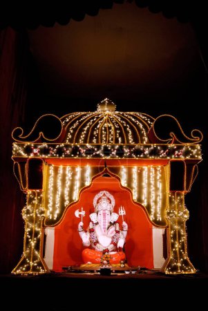 Téléchargez les photos : Idole du seigneur Ganesh dieu tête d'éléphant maintenu dans un cadre joliment décoré de lumières illuminées, festival Ganpati à Pune, Maharashtra, Inde - en image libre de droit