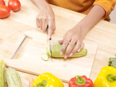 Téléchargez les photos : Young lady slicing cucumber on cutting board MR702U - en image libre de droit