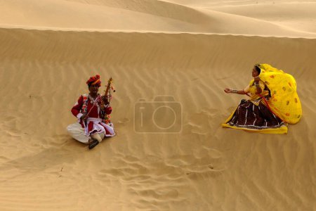 Foto de Pareja tocando música folclórica y bailarina en dunas de arena, Jaisalmer, Rajasthan, India - Imagen libre de derechos