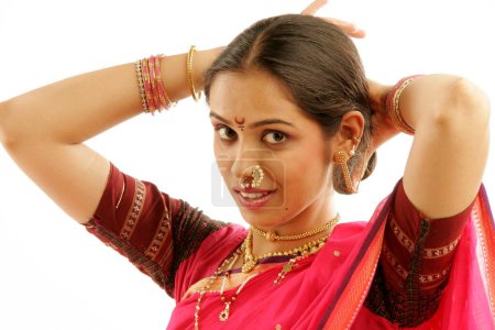 South Asian Indian Maharashtrian girl wearing traditional navwari nine yard sari with appropriate jewellery trying to adjust long hair Platte straight and proper