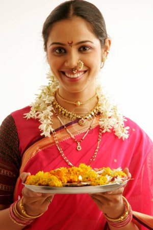 South Asian Indian Maharashtrian girl wearing traditional navwari nine yard sari with appropriate jewellery holding pooja thali in hand 