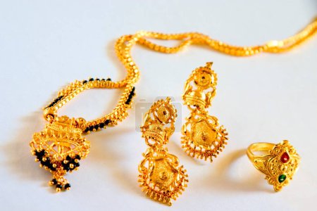 Foto de Collar de perlas de oro y negro mangalsutra novia hindú símbolo de matrimonio anillo de bodas de oro con pendientes joyas de imitación sobre fondo blanco - Imagen libre de derechos