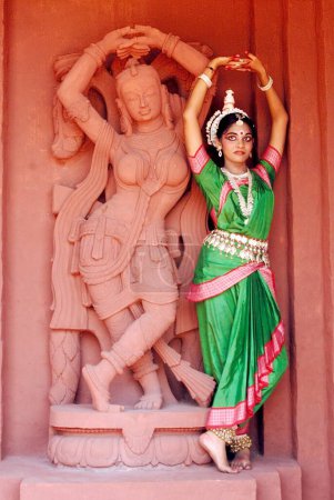 Photo for Woman performing classical traditional Odissi dance at statue on stage - Royalty Free Image