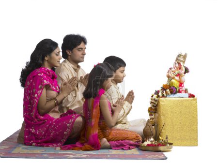 Foto de Sur de Asia familia india con padre madre hijo e hija sentado orando al señor Ganesha - Imagen libre de derechos