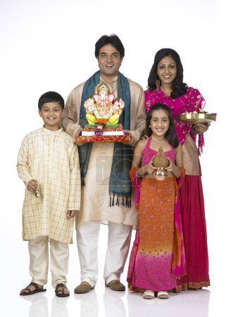 Photo for South Asian Indian family with father mother son and daughter holding statue of lord Ganesha and Kalash Aarti thali - Royalty Free Image