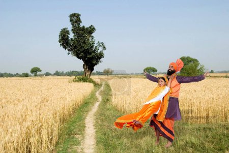 Foto de Bailarines realizando danza folclórica bhangra en campo de trigo - Imagen libre de derechos
