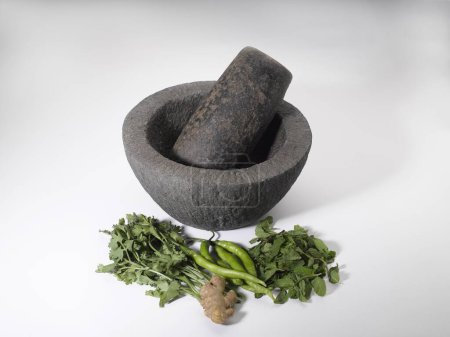 Photo for Spices , old stone grinder with ginger green chillies coriander and mint leaves on white background - Royalty Free Image
