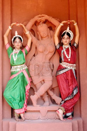 Foto de Mujeres realizando danza clásica tradicional Odissi delante de la estatua en el escenario - Imagen libre de derechos
