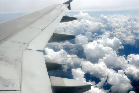 Téléchargez les photos : Vue du nuage dans le ciel bleu et de l'aile de l'avion depuis la fenêtre de l'avion - en image libre de droit