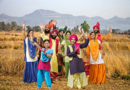 Foto de Familia Sikh con bailarines realizando danza folclórica bhangra en hierba seca - Imagen libre de derechos