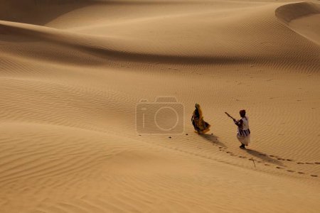 Foto de Pareja tocando música folclórica y bailando en dunas de arena, Jaisalmer, Rajasthan, India - Imagen libre de derechos