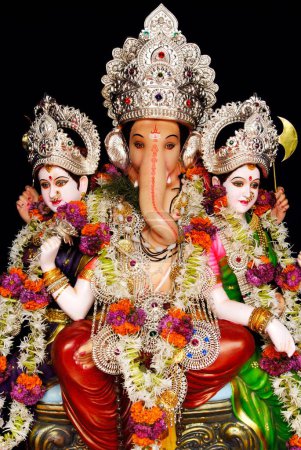 Photo for Richly decorated idol of lord ganesh elephant headed god sitting with his two consorts Riddhi and Siddhi for Ganpati festival at Mandai , Pune , Maharashtra , India - Royalty Free Image
