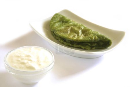 Indian cuisine , fast food crispy Palak Spinach Puri with curd served in dish on white background
