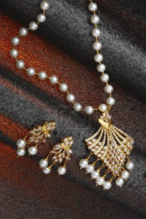 Foto de Collar de joyas de oro diamante con diamantes y perlas orejeras sobre fondo rojo negro - Imagen libre de derechos