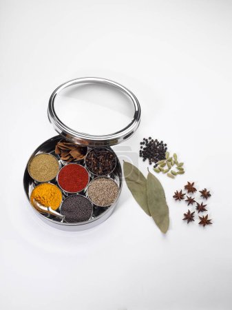 Different types of spices in bowls in stainless steel box on white background
