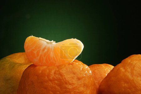 Foto de Una pieza de fruta naranja sobre otras naranjas sobre fondo verde negro - Imagen libre de derechos