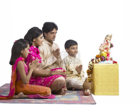 Foto de Sur de Asia familia india con padre madre hijo e hija sentado orando al señor Ganesha - Imagen libre de derechos