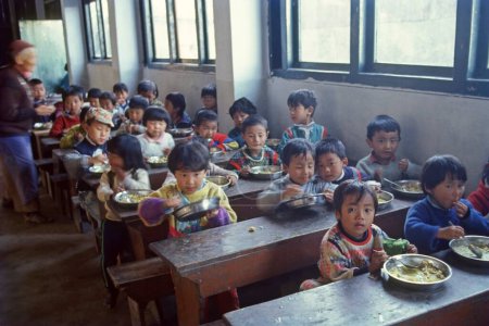 Téléchargez les photos : Un enfant tibétain déjeune dans un centre de réfugiés - en image libre de droit