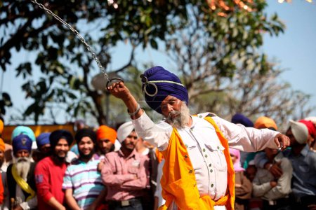 Téléchargez les photos : Guerrier nihang ou sikh effectuant des cascades avec chaîne pendant les célébrations Hola Mohalla à Anandpur sahib dans le district de Rupnagar, Punjab, Inde - en image libre de droit