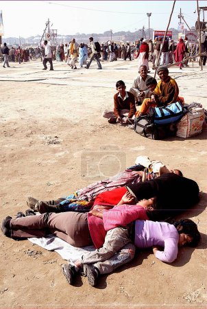Téléchargez les photos : Une famille fatiguée dort sur les rives du Gange, Ardh Kumbh Mela, l'une des plus grandes fêtes religieuses au monde à Allahabad, Uttar Pradesh, Inde - en image libre de droit