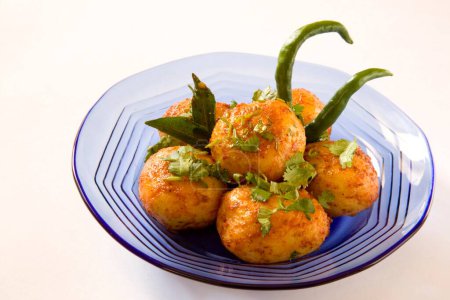 Foto de Cocina india tandoori masala aloo potato con hojas de cilantro hojas de curry y chiles verdes servidos en plato, India - Imagen libre de derechos