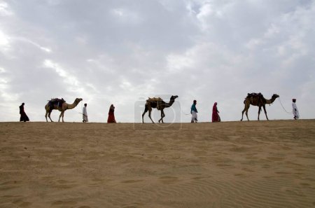 Téléchargez les photos : Camels with men and women in Thar desert Jaisalmer Rajasthan India Asia - en image libre de droit