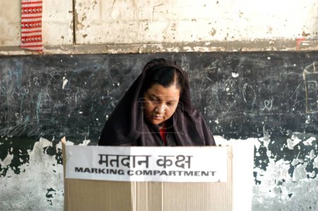 Foto de Una mujer musulmana emitiendo su voto durante las elecciones indias de Loksabha de 2004 en la cabina electoral de Shivaji Nagar, Govandi, Mumbai Bombay, Maharashtra, India - Imagen libre de derechos