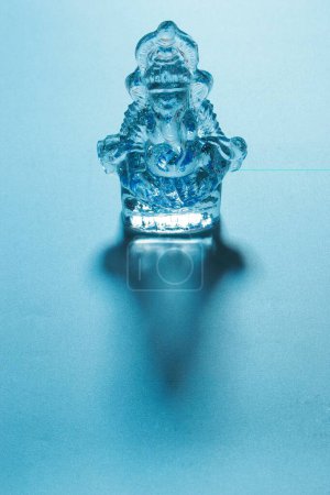 Photo for Crystal glass idol of lord Ganesh elephant headed god with shadow on bluish background - Royalty Free Image