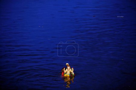 Idol of Lord Ganesha ganpati Hindu deity being immersed in Powai lake ; Bombay Mumbai ; Maharashtra ; India