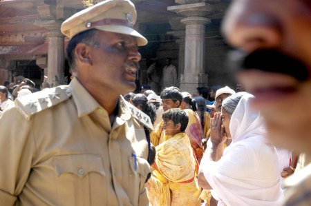 Téléchargez les photos : Pilgrim se faufile comme policier est absorbé dans ses propres pensées pendant Mastakabhishek qui se produit après tous les 12 ans, Shravanbelgola, Karnataka, Inde - en image libre de droit