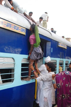 Foto de Los hombres arrastrando a la mujer tratando de subir en el techo del tren en la estación de Jodhpur; Rajastán; India - Imagen libre de derechos